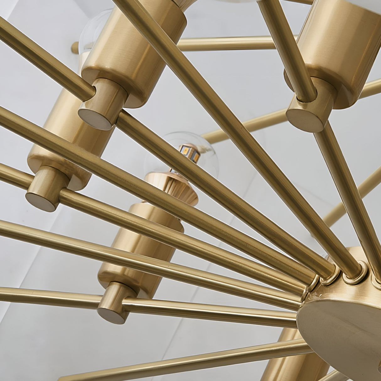 Close-up of the Caldrin 10 Light Tiered Panel Alabaster Chandelier in Soft White & Brass, featuring multiple metal arms with bulbs, set against a white ceiling.