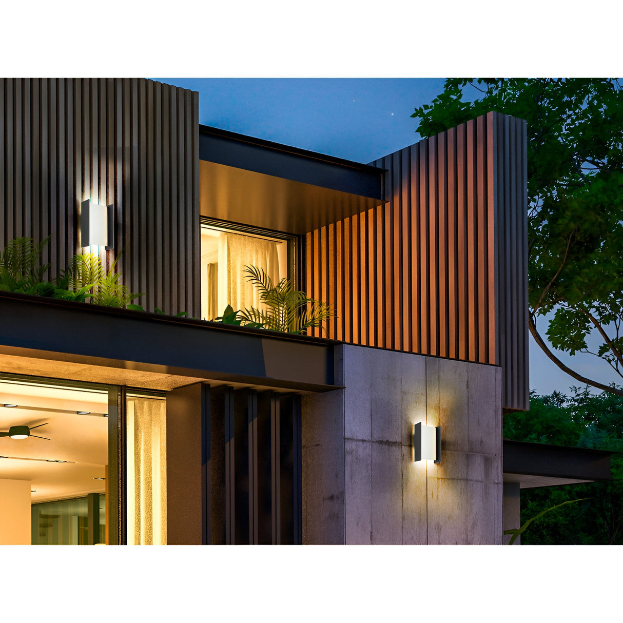 Modern house exterior at dusk with vertical wooden slats, large windows, warm lighting, and two Matia Outdoor LED Wall Light 18W 3000K - Dark Grey fixtures brightening the facade. Lush green plants enhance the contemporary design.