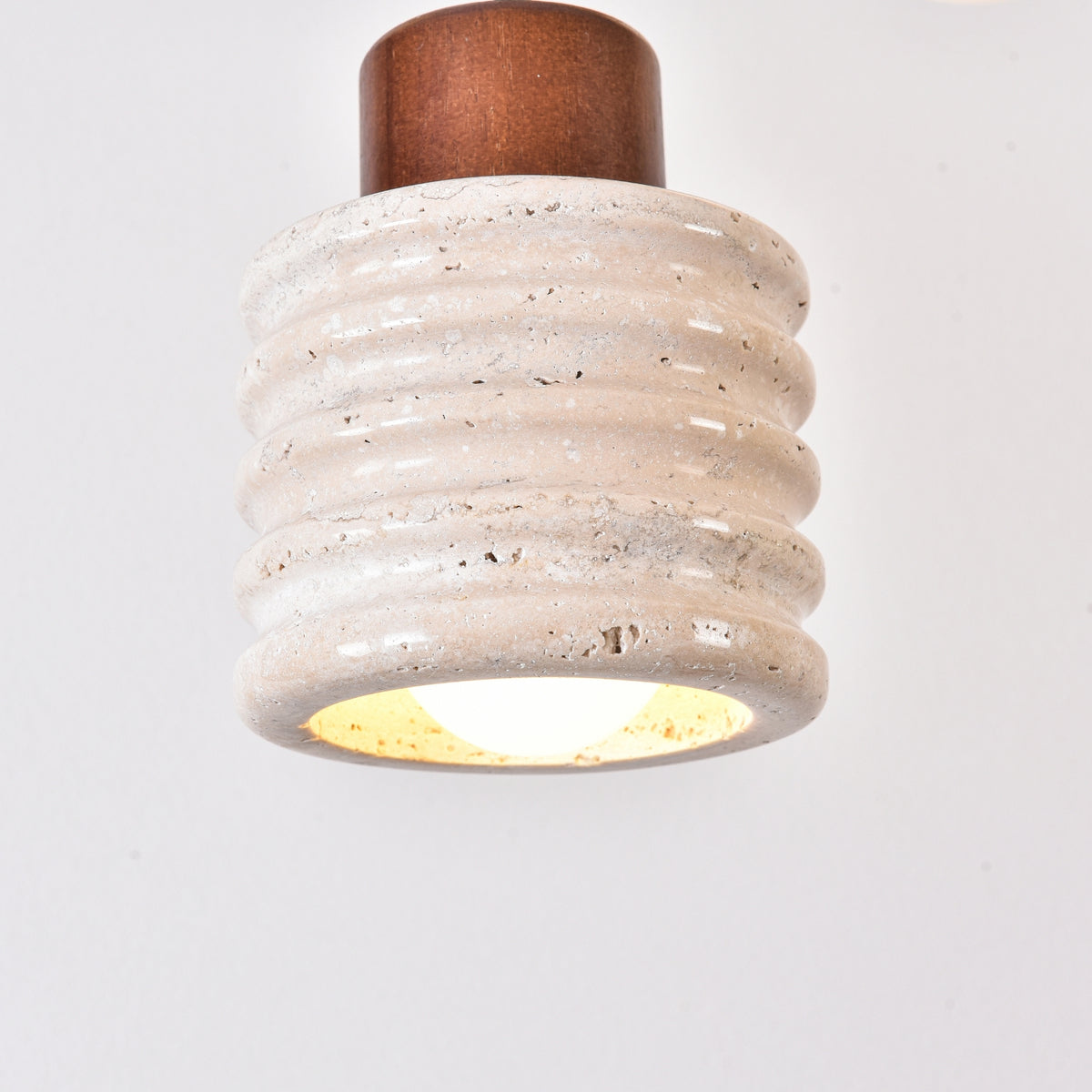Rivano Ribbed Travertine Pendant Light with ribbed light beige stone drum, walnut wood top, and glowing E27 bulb, shown against a plain white background.