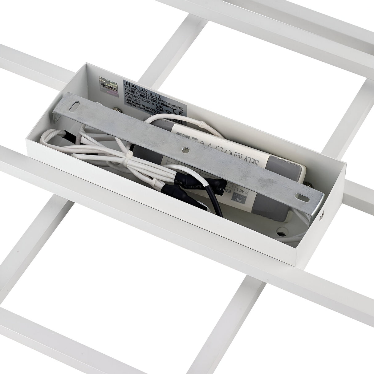 A detailed view of the wiring and electrical component housing of the Prios LED Ceiling Light 31W 3000K - White from IKEA. The metal and plastic components are neatly arranged inside a rectangular box, revealing wires and circuit details. This setup is encased in a grid structure, enhanced by opal-colored diffusers for a minimalist design.