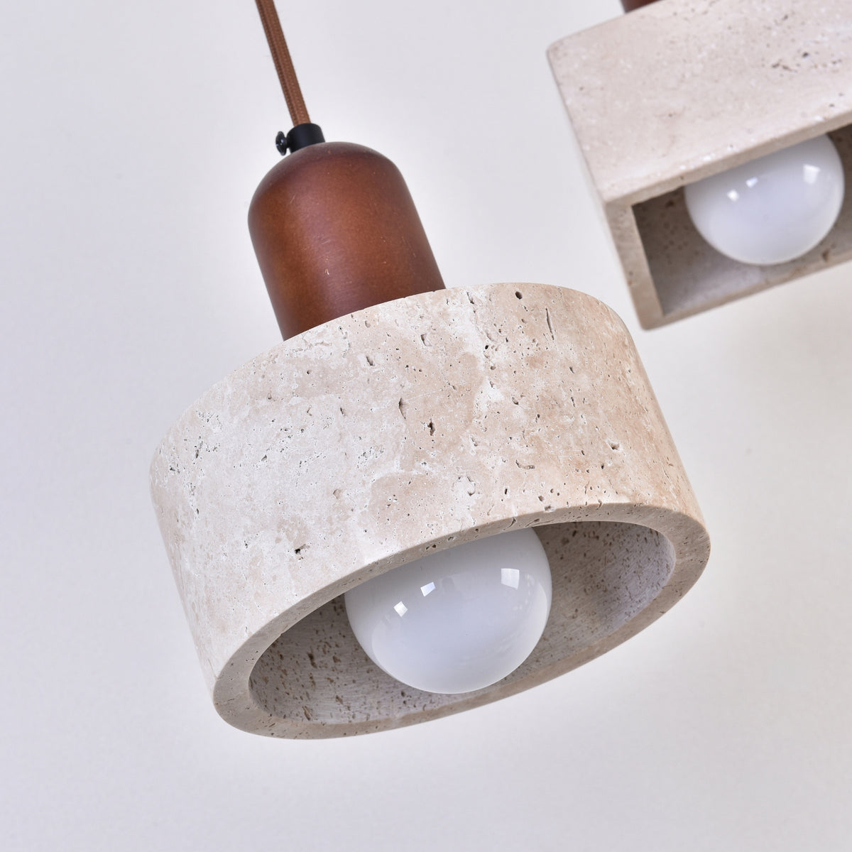 Lunaro 1 Light Travertine Pendant Light with walnut wooden top and light beige cylindrical stone shade, exposed E27 bulb, on a brown fabric cable.