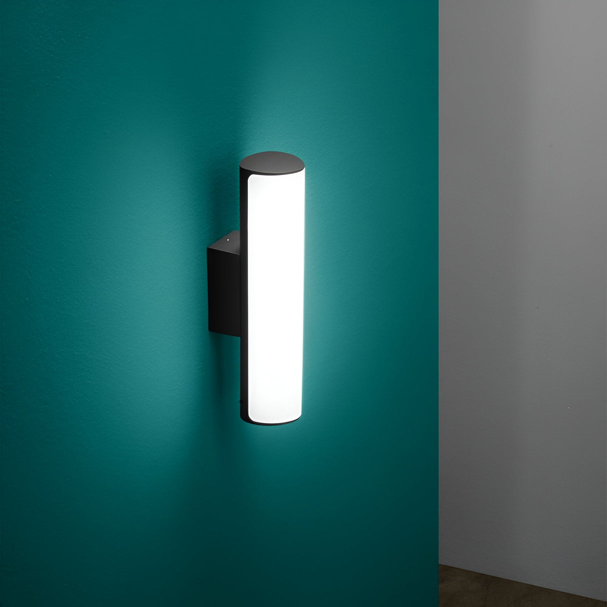 The Glintis LED Bathroom Mirror Light 9.5W 3000K in anthracite elegantly illuminates the teal wall with its minimalist cylindrical design, featuring a sleek mounting bracket. This product provides an energy-efficient and soft ambient glow that enhances any space.
