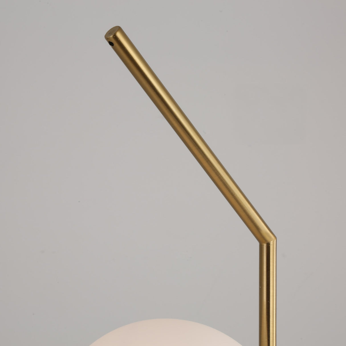 A close-up of the Vetra 1 Light Opal Glass Table Lamp in gold, showcasing its angled metal stem and partially visible white opal glass shade against a plain light gray background.