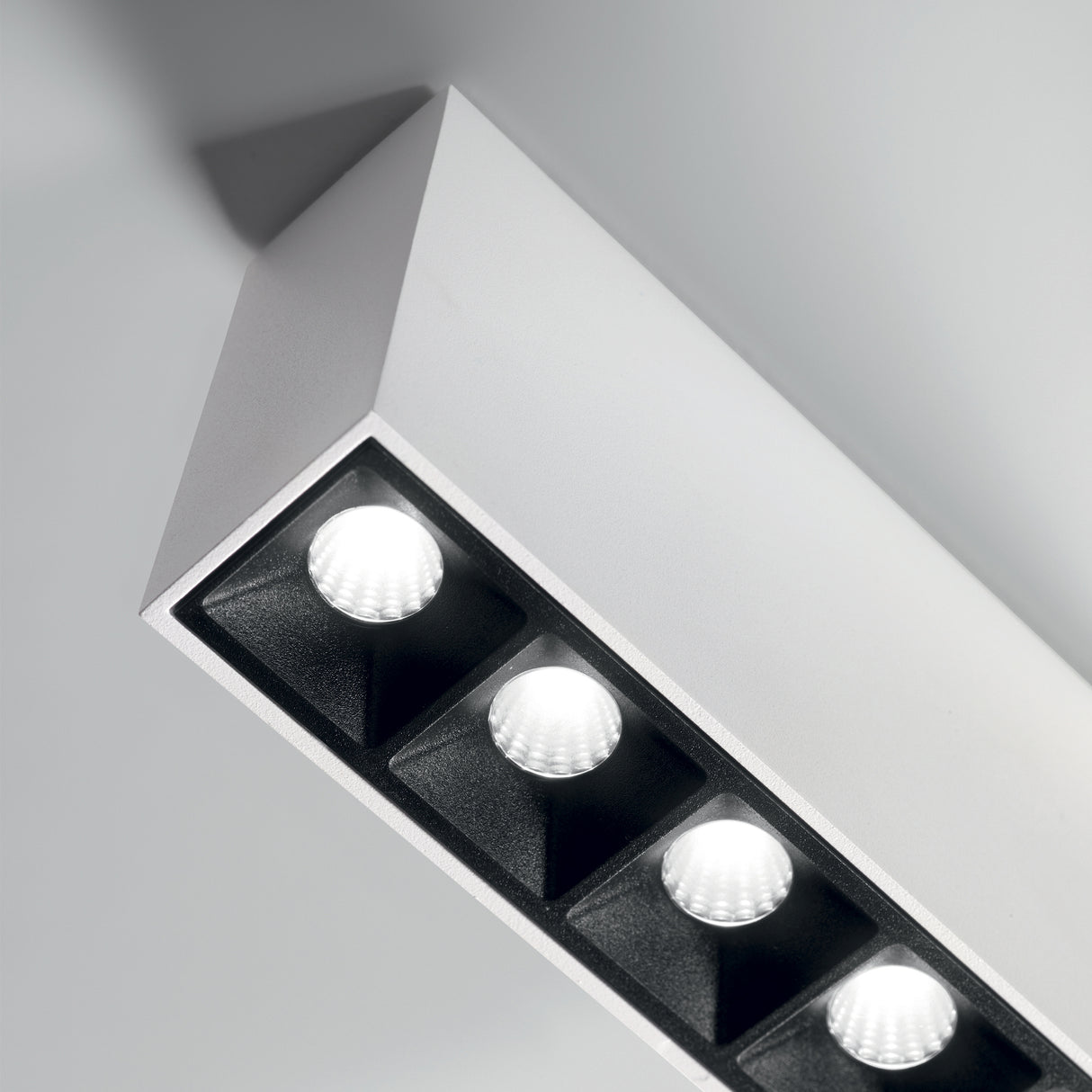 Introducing the Phosix LED Downlight, a modern rectangular ceiling fixture equipped with four recessed 12W LED lights that emit a warm 3000K glow. This energy-efficient lighting solution features a sleek, minimalist design in a refined white finish, perfectly complementing any light-colored ceiling with its modern elegance.