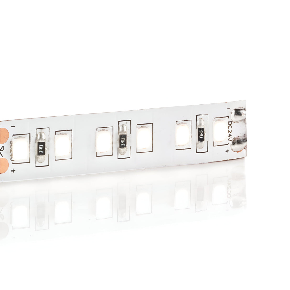 Close-up of the Ecliptus 24V Dimmable LED Strip Light 40W IP20 5m - 3000K, showcasing exposed circuit components such as small resistors and LED lights, placed on a reflective surface. The energy-efficient lighting strip is partially visible and positioned diagonally.
