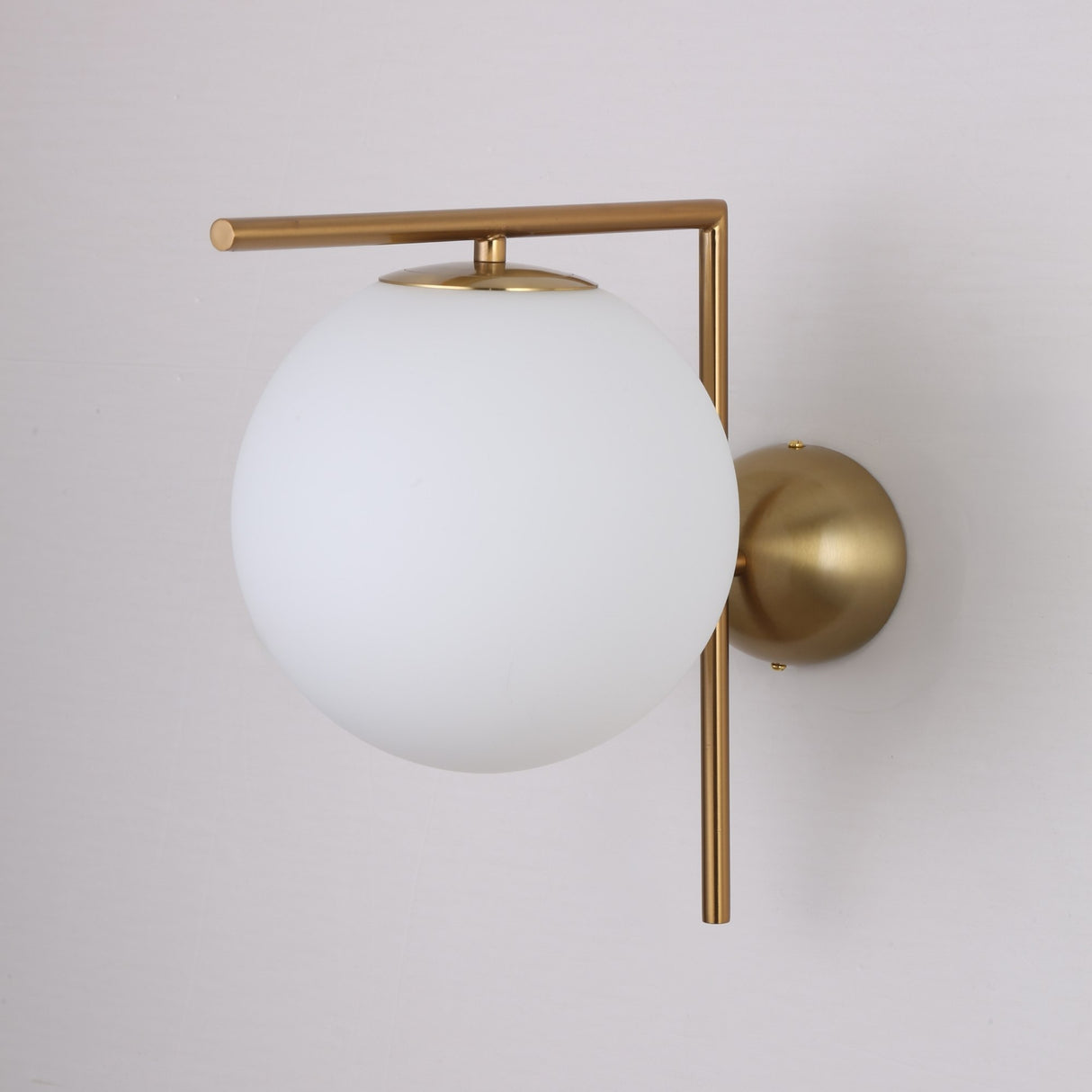 The Vetra 1 Light Opal Glass Wall/Semi-Flush Ceiling Light in gold features a round white opal glass globe and sleek gold metal fixture, elegantly mounted on a light-colored wall.