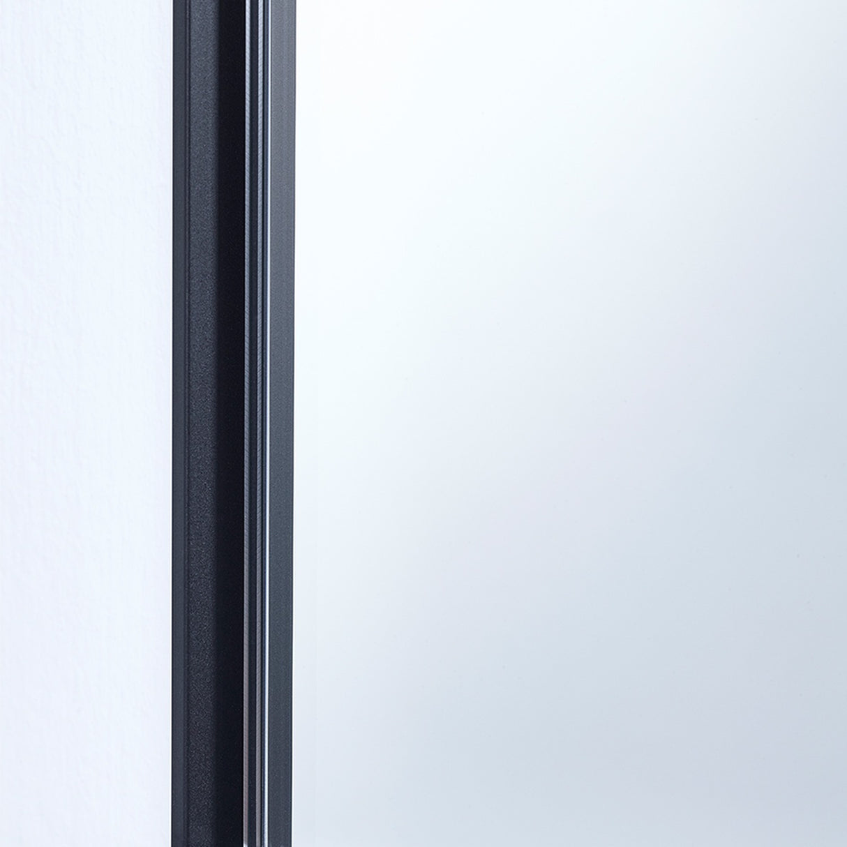 Close-up of the Lucka Black Slim Framed Full Length Mirror's edge, showing the thin black metal frame flush against the glass, set against a white wall.