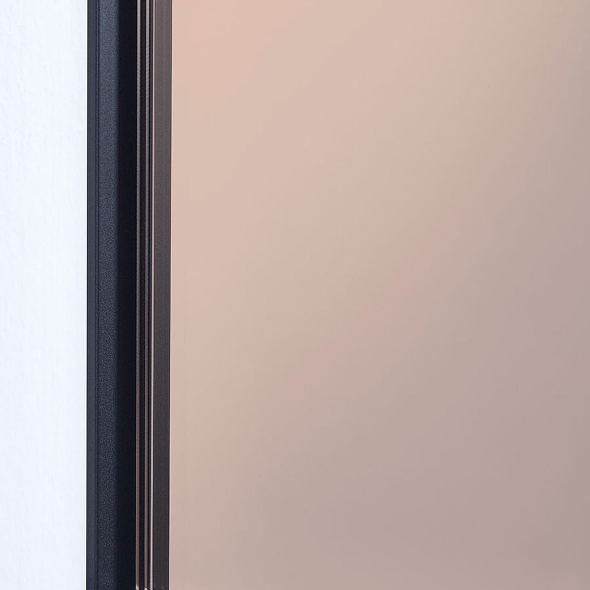Close-up of the Lucka Bronze Black XXL full length mirror, showing the black metal frame edge against the bronze tinted glass.