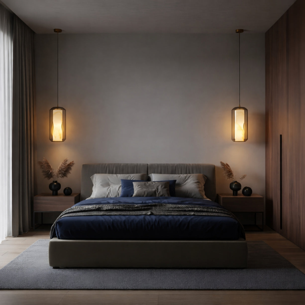 A modern bedroom with a large bed, dark blue bedding, gray headboard, and wooden nightstands features globe lamps and a Vale 1 Light Faceted Alabaster Single Pendant Light in Soft White. Neutral tones and soft lighting add coziness over the wood floor and gray rug.