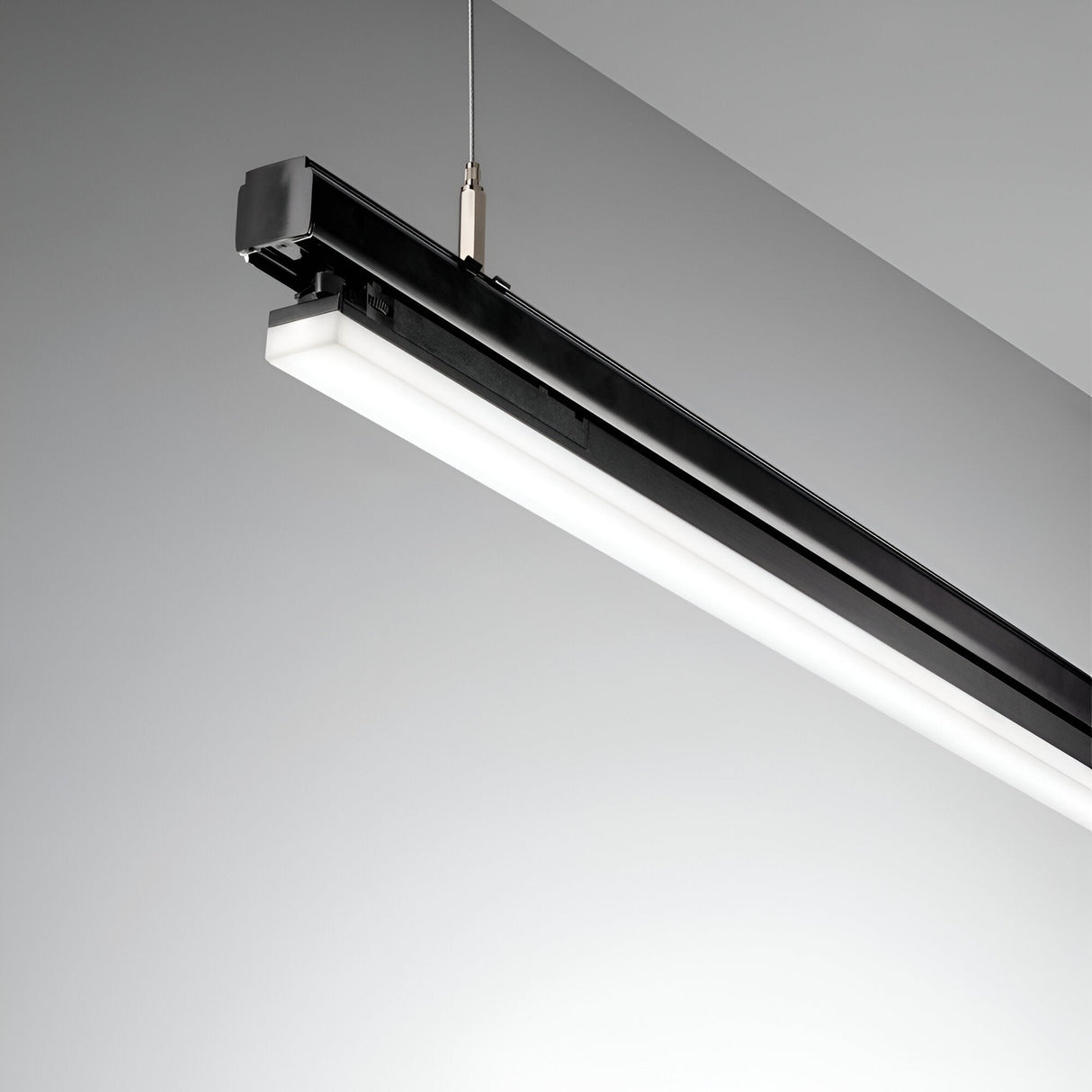 A contemporary and energy-efficient black track fixture, featuring the Dune Wide 3-Phase LED Linear Track Light 40W 3000K, 1125cm, adorns a minimalist ceiling against a light gray backdrop, ideal for commercial lighting.