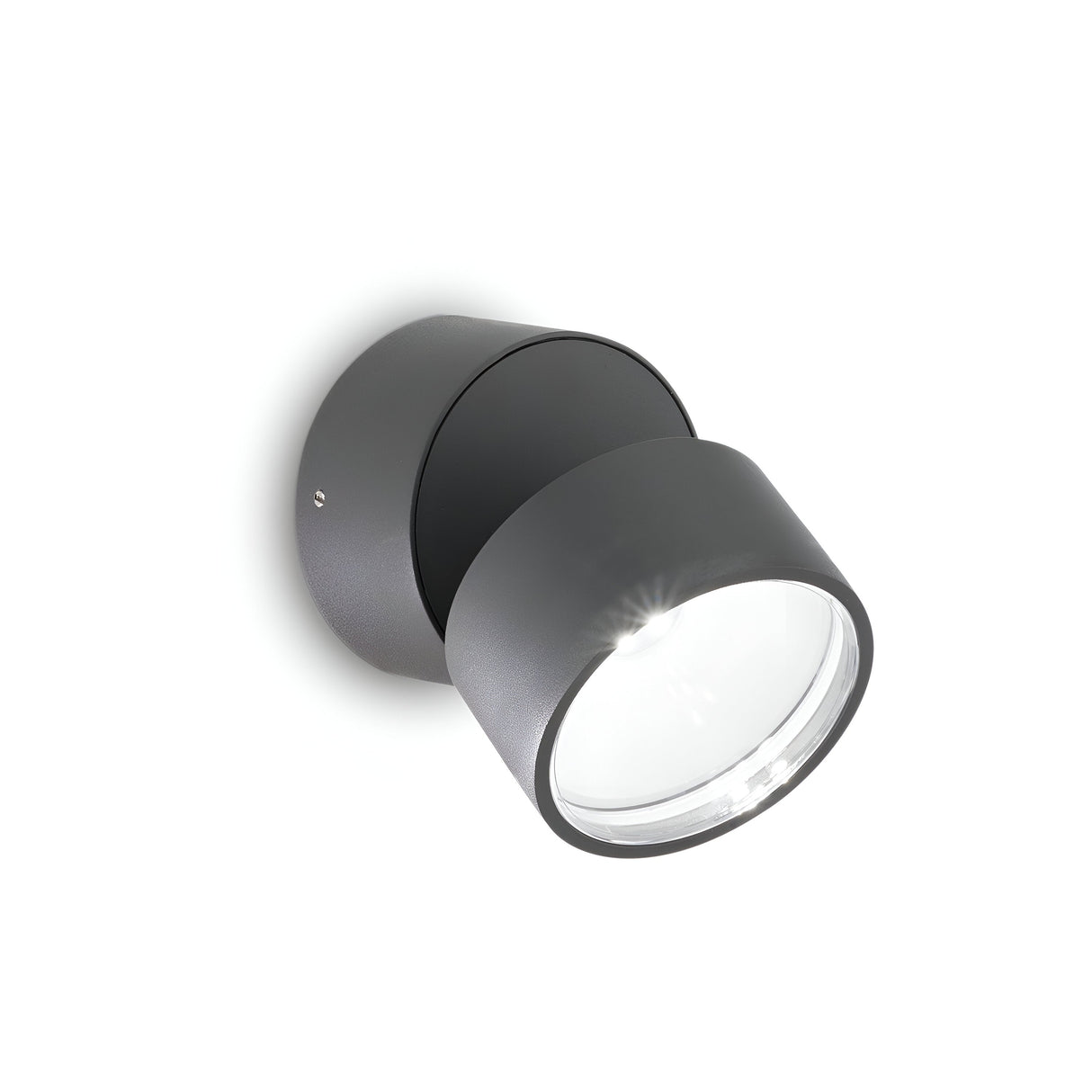 Introducing the Arcane Round Outdoor LED Single Spotlight 7W 3000K in grey: a contemporary, cylindrical wall-mounted fixture with a circular transparent lens. Designed to angle slightly away from the wall, it projects light outward. Its energy-efficient lighting and IP54-rated construction make it perfect for any exterior setting against a white background.