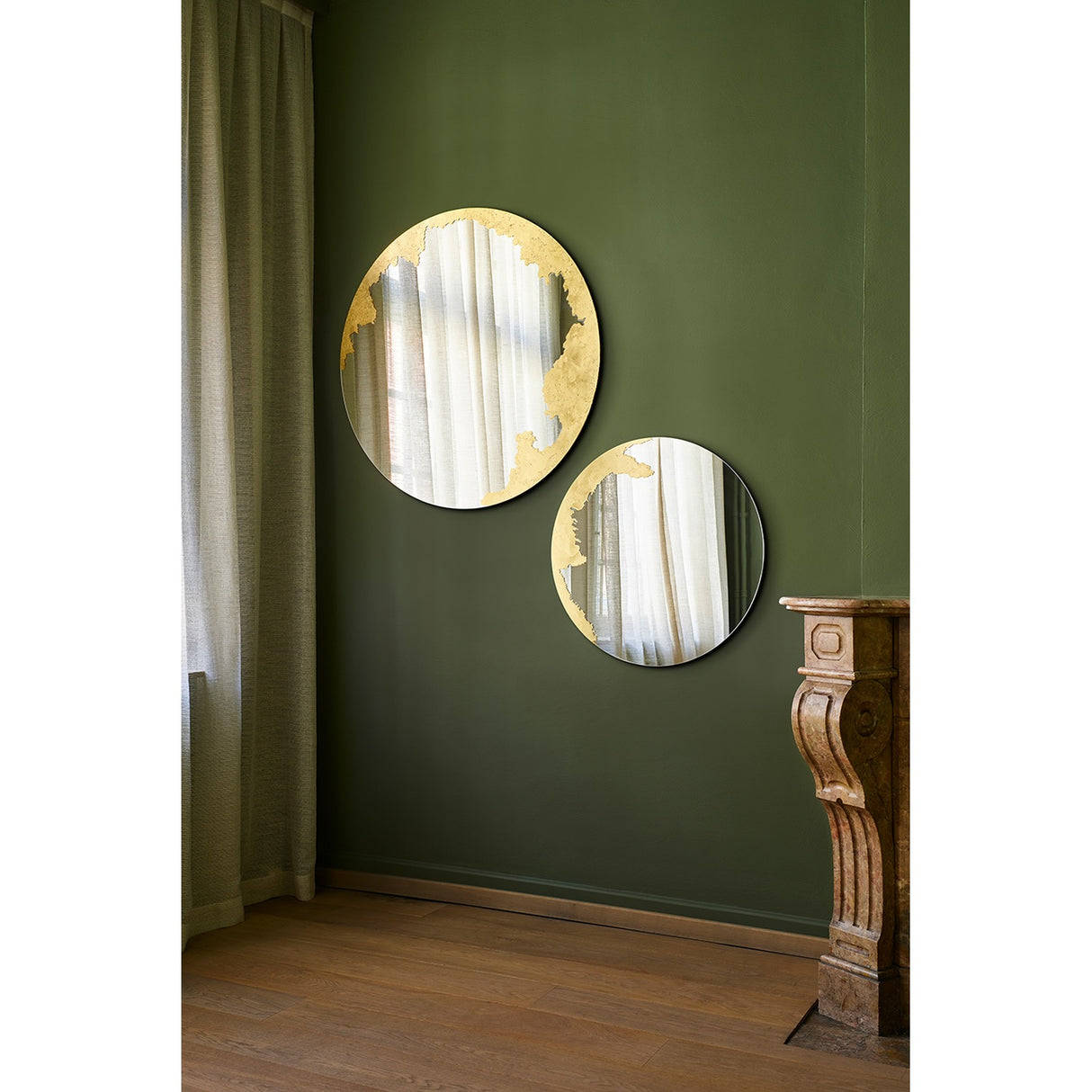 Ornato Gold Leaf Round Rotating Wall Mirror 70cm shown in pairs on a green wall, each frameless round mirror with an irregular hand-applied gold leaf patch on the rim.