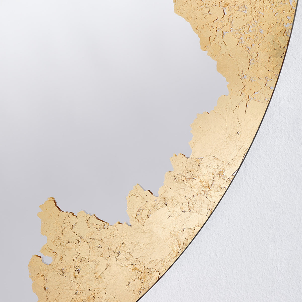 Close-up of the Ornato Gold Leaf Round Rotating Wall Mirror 70cm, showing the frameless glass edge with hand-applied gold leaf in an irregular, torn pattern.
