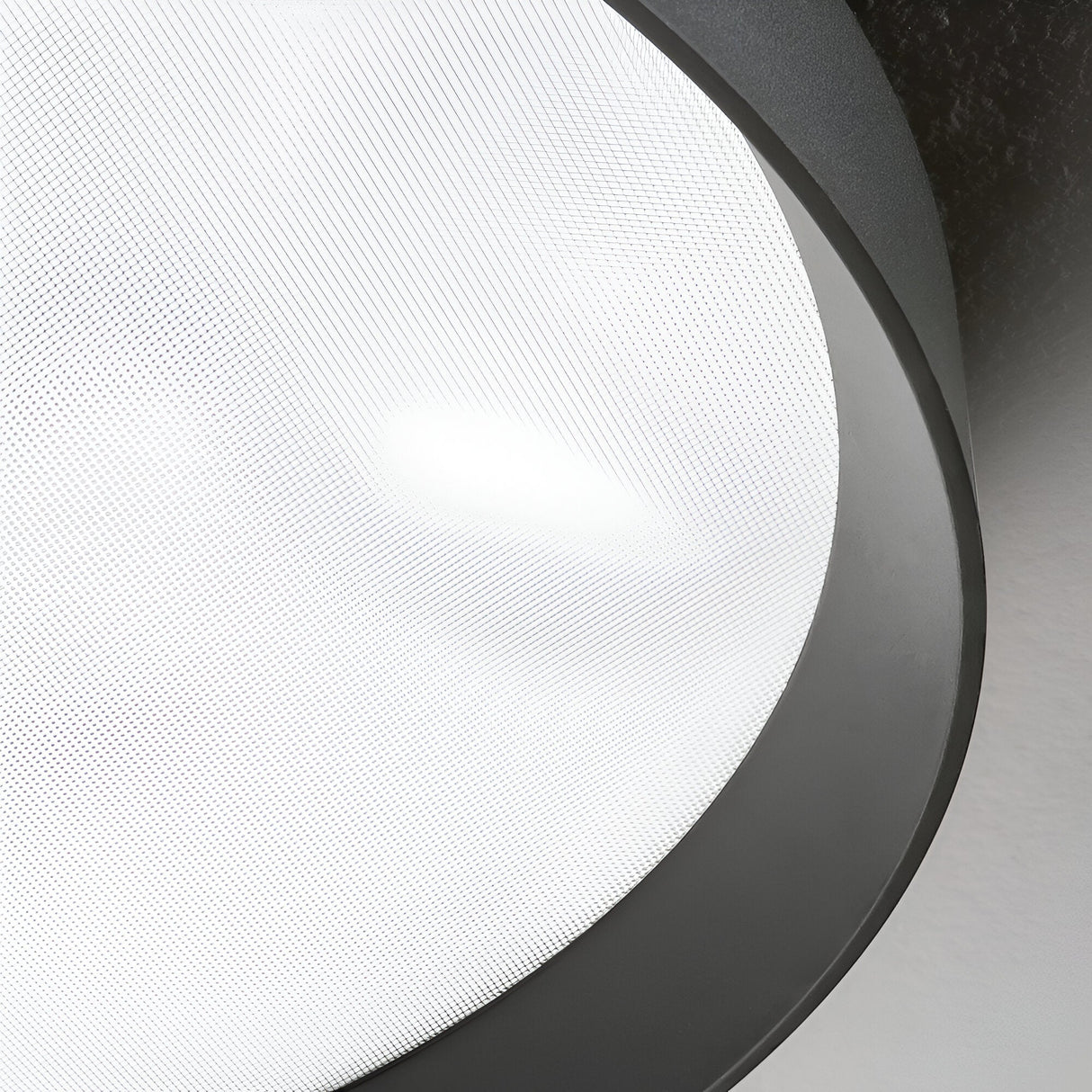 A close-up of the Spark LED Flush Light 53W 3000K - Black, 60cm showcases its modern design, featuring a round frosted glass surface encased in a slim black metallic rim. Utilizing energy-efficient LED technology, it evenly diffuses light to create a soft glow against the ceiling.