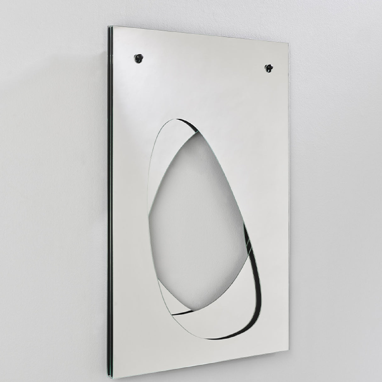 Infinito Precision Cut Void Wall Mirror 100cm, a rectangular frameless mirror with a white panel and an organic cut-out void revealing recessed mirrored glass, shown at an angle against a plain wall.