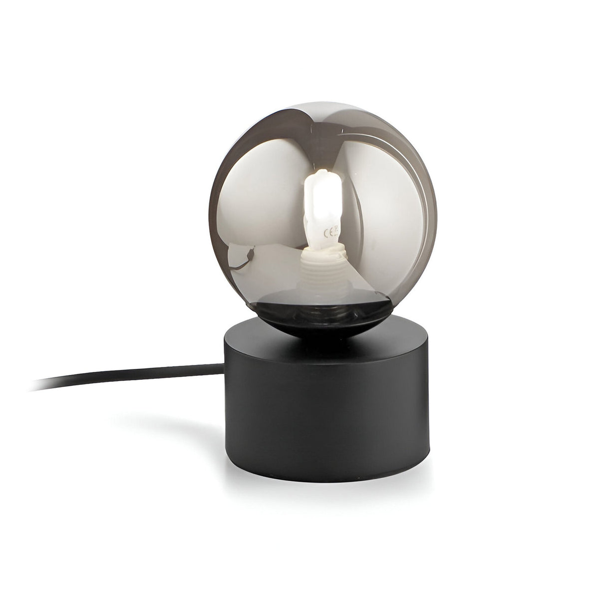 The Solana Small Table Lamp - Black boasts a contemporary design with a round, smoked glass diffuser on top of a cylindrical black base. When illuminated, the light glows gently through the translucent shade. A sleek black power cord seamlessly extends from the base, complementing its modern aesthetic.
