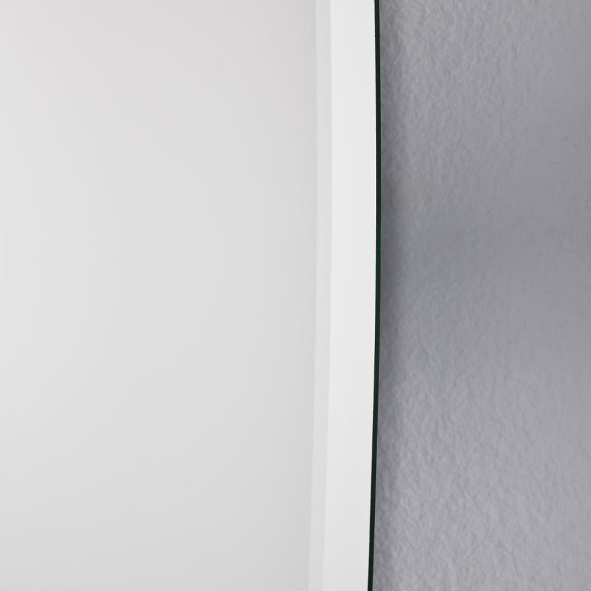 Close-up of the bevelled edge against a textured wall, the ground angle catching the light along the contour.