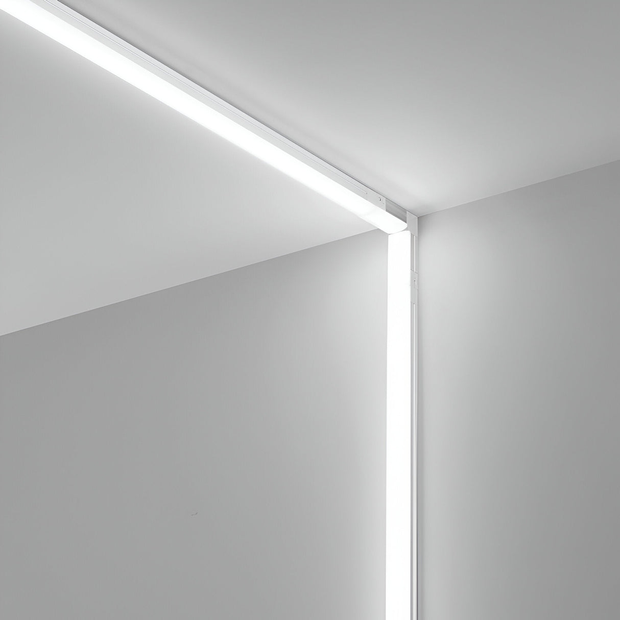 A minimalist interior corner showcases pristine white walls and ceiling, complemented by sleek linear LED strip lights seamlessly integrated along the junctions. These emit a gentle glow at 3000K. The Nocturne Corner Connector 3000K 1W in White elevates the design by highlighting the architectural lines of this lighting setup.
