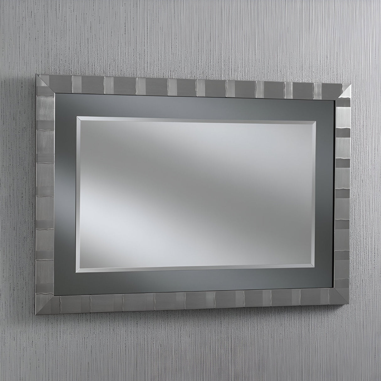 The Vault Rectangle Wall Mirror - Grey Lacquered, featuring a metallic frame with a grid pattern and beveled edge, is mounted on a textured gray wall, making it an ideal decorative addition to a contemporary living room.