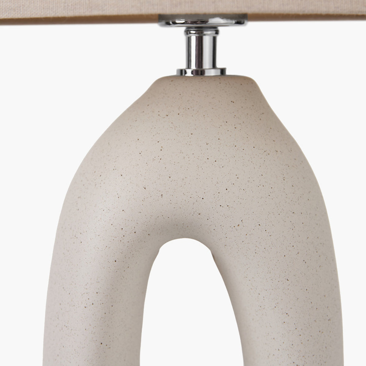 Close-up of the Laila Natural Beige Organic Tall Ceramic Table Lamp base, showing speckled beige ceramic with an arched cut-out and chrome fitting beneath a linen shade.