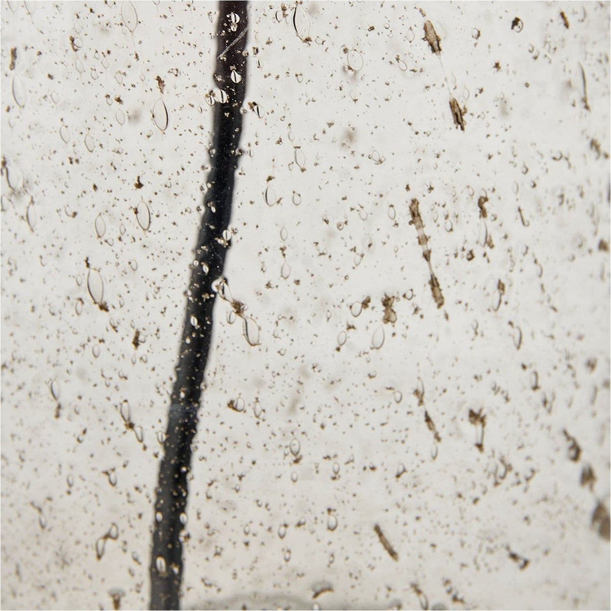 Close-up macro detail of the Ophelia Small Grey Bubble Glass Table Lamp Base showing its textured bubble glass surface with a dark cord running vertically through it.