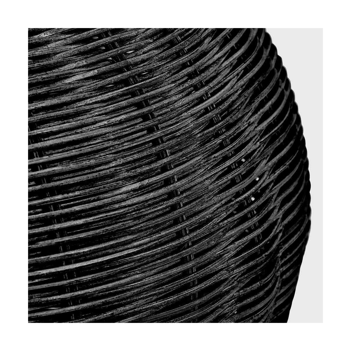 Close-up of the Allona Black Rattan Table Lamp base, showing tightly woven black rattan strands in a spiralling texture.