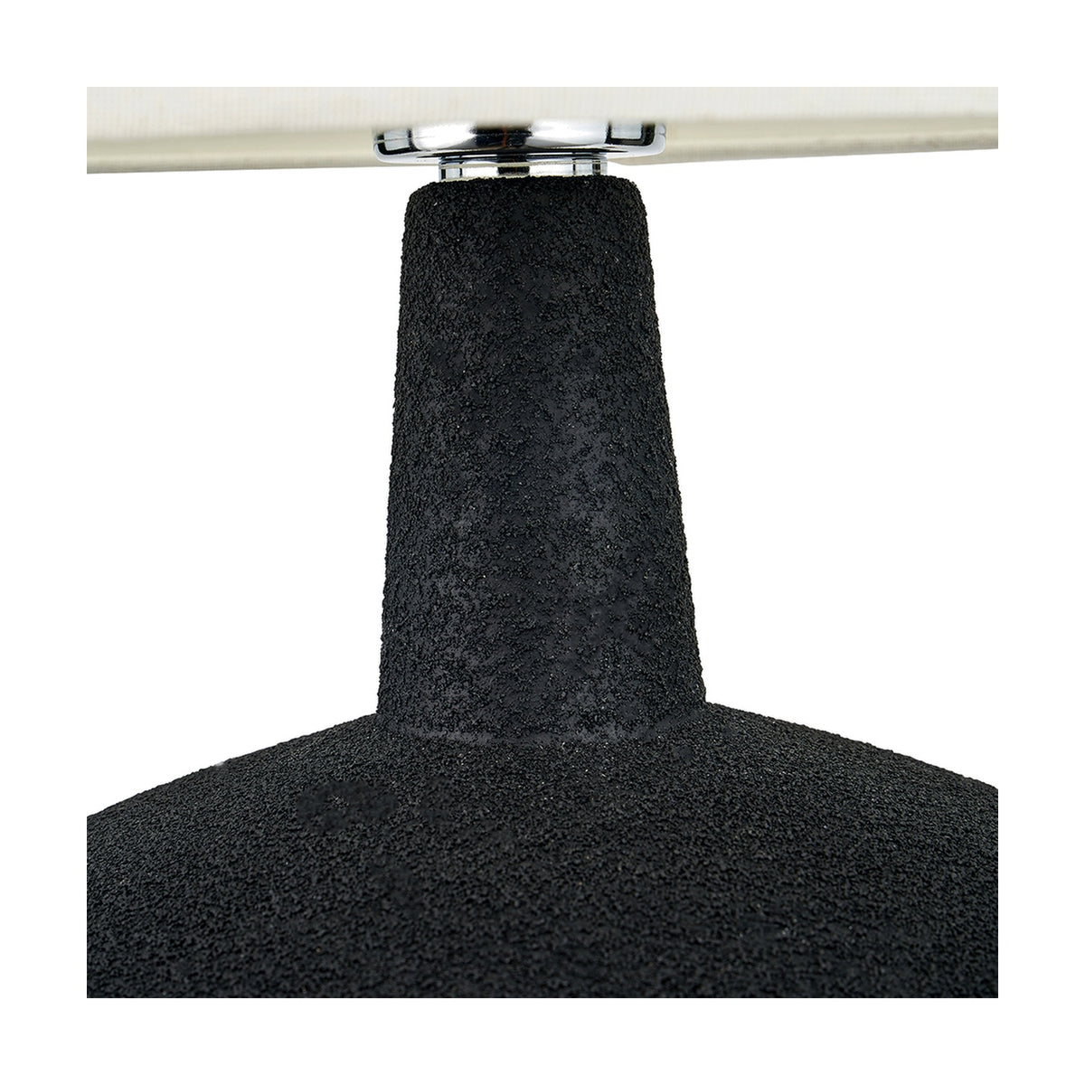 Close-up of the Elio black ceramic table lamp base, showing textured surface, tapered neck, and chrome fitting beneath a cream fabric shade.