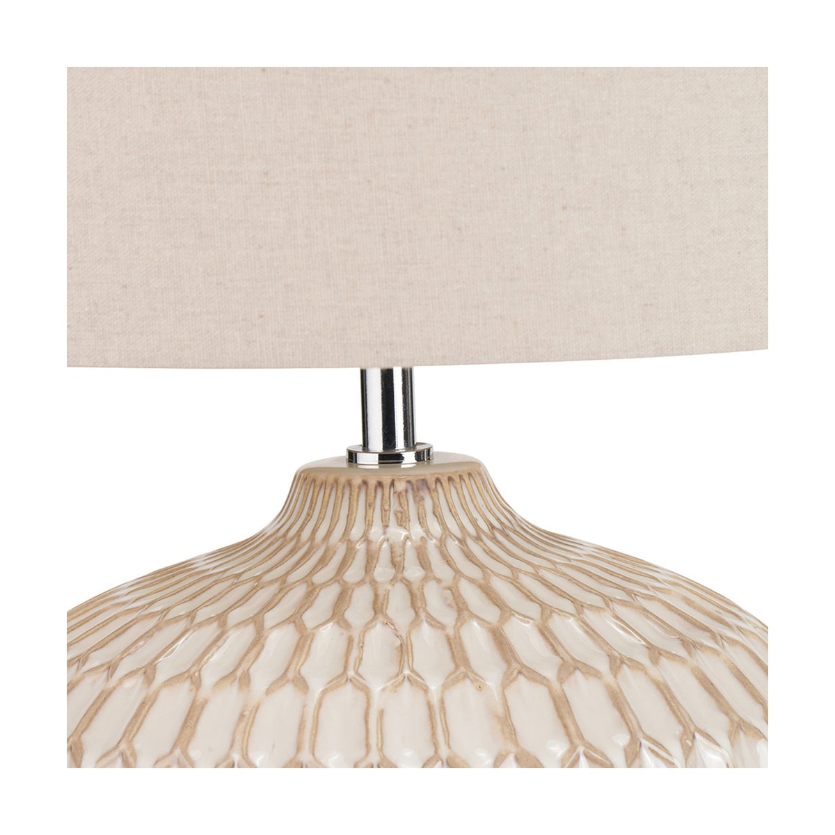 Close-up of the Cassius table lamp base showing textured warm white glazed ceramic with honeycomb ridges, a chrome neck, and a linen drum shade.