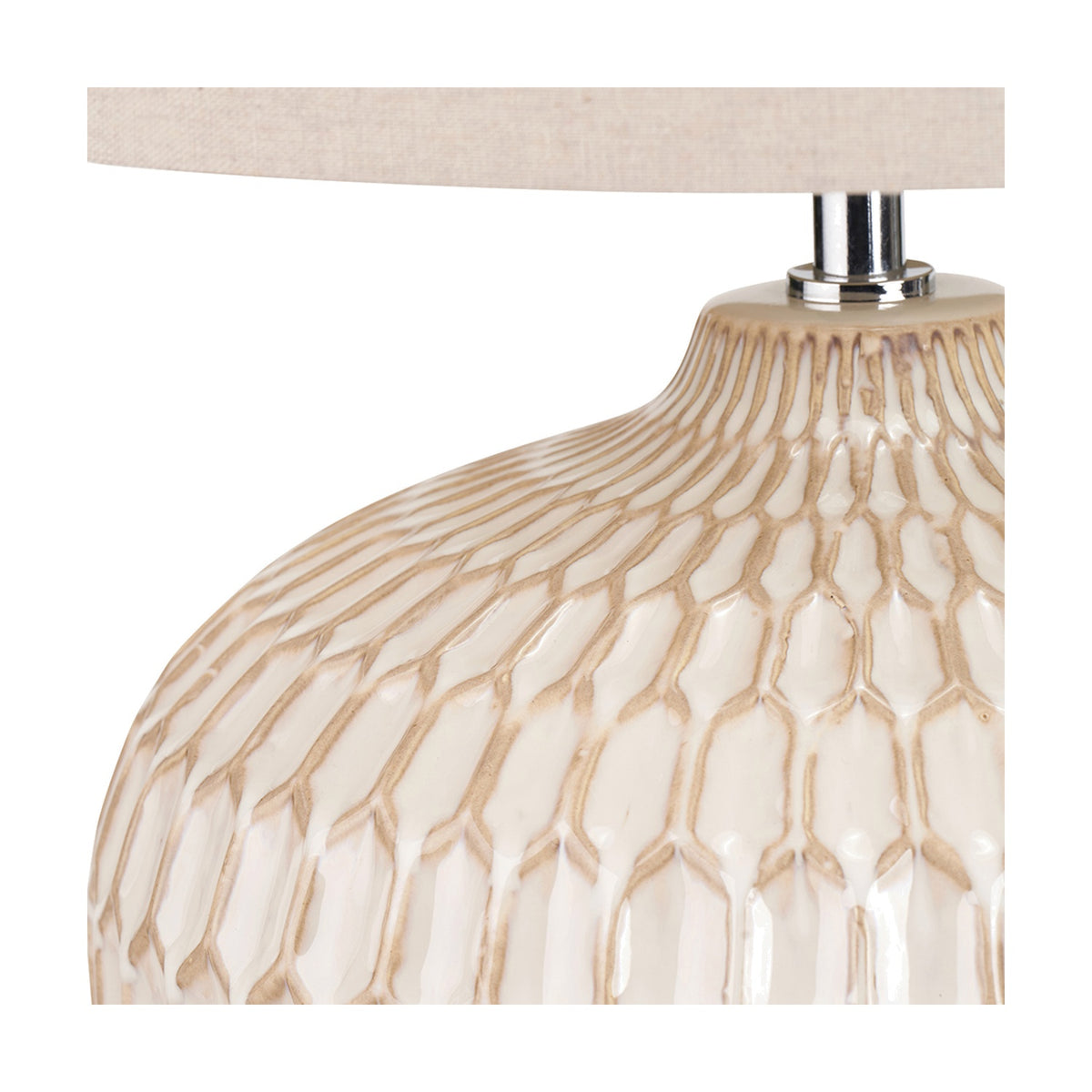 Close-up of the Cassius table lamp's ceramic base in warm white with a raised honeycomb texture, shown beneath a linen shade with chrome fitting.