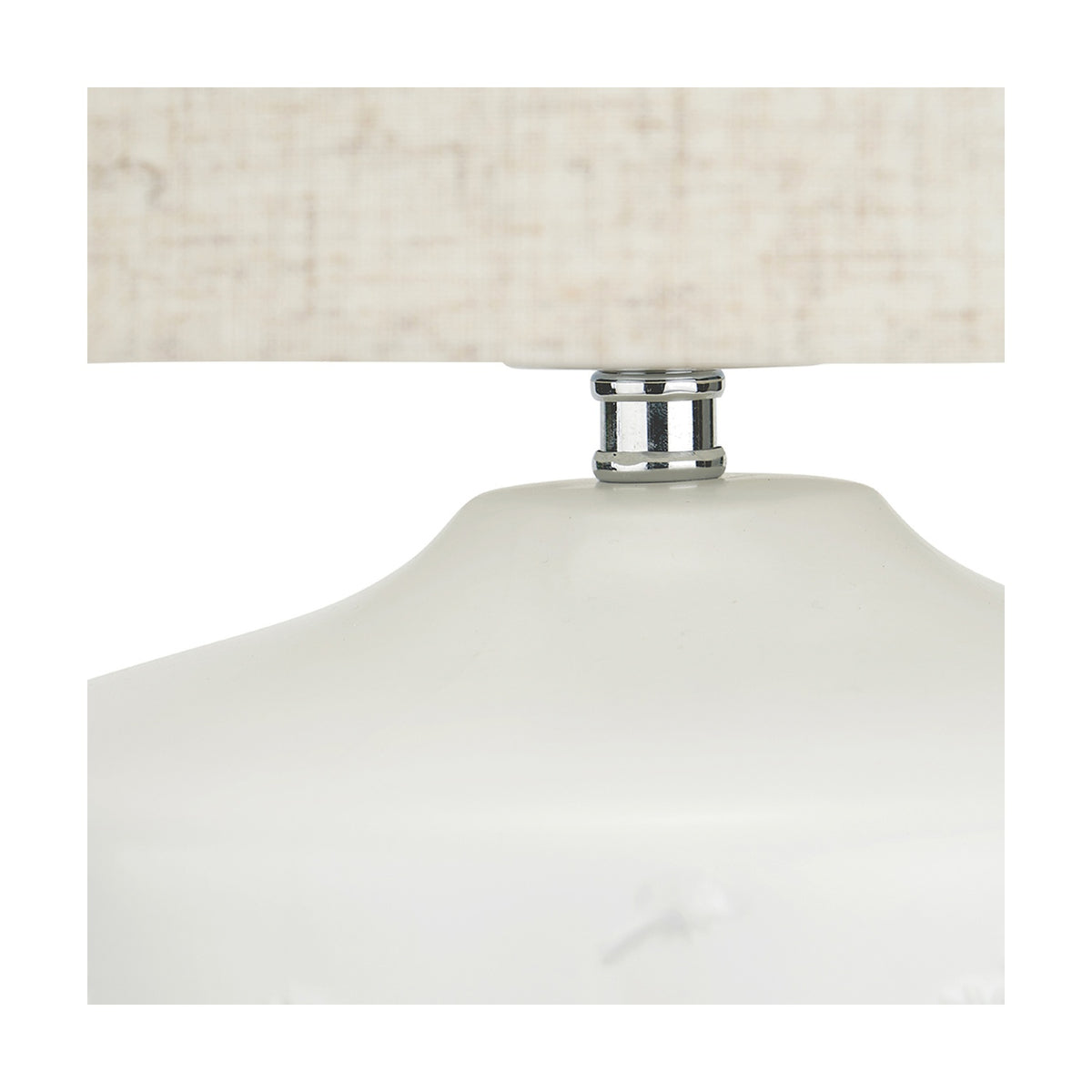 Close-up of the Flora White Small Floral Ceramic Table Lamp, showing the chrome connector joining the white ceramic base to a neutral linen shade.