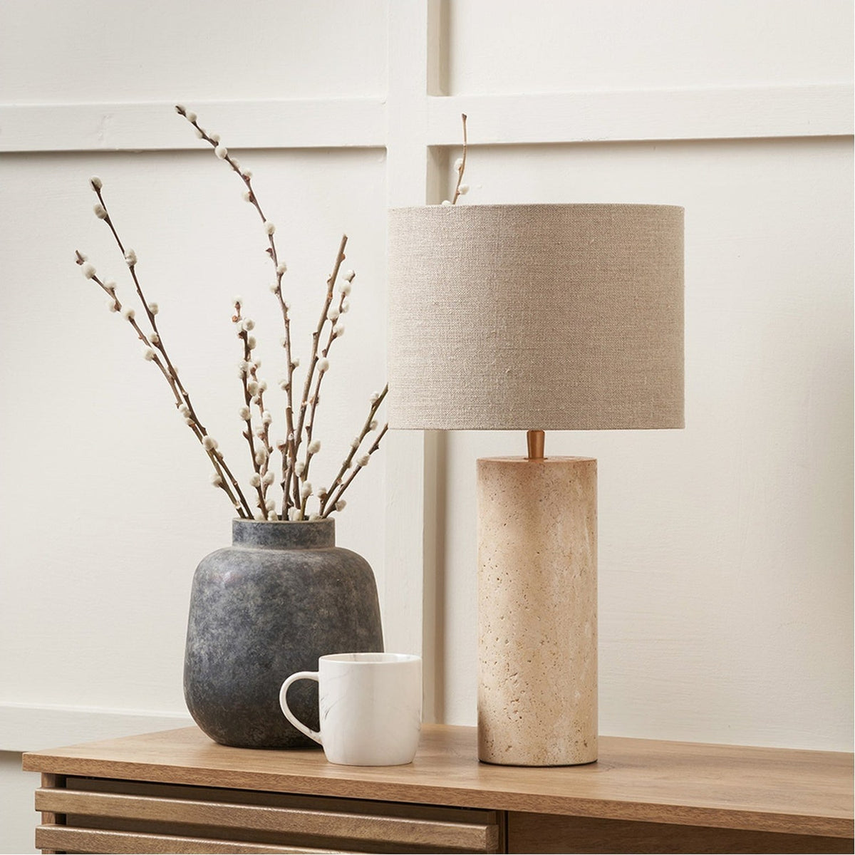 Kanoa Limestone Cylinder Table Lamp, 47cm, with natural stone base and linen drum shade, styled beside a grey marble vase and mug on a wooden sideboard.