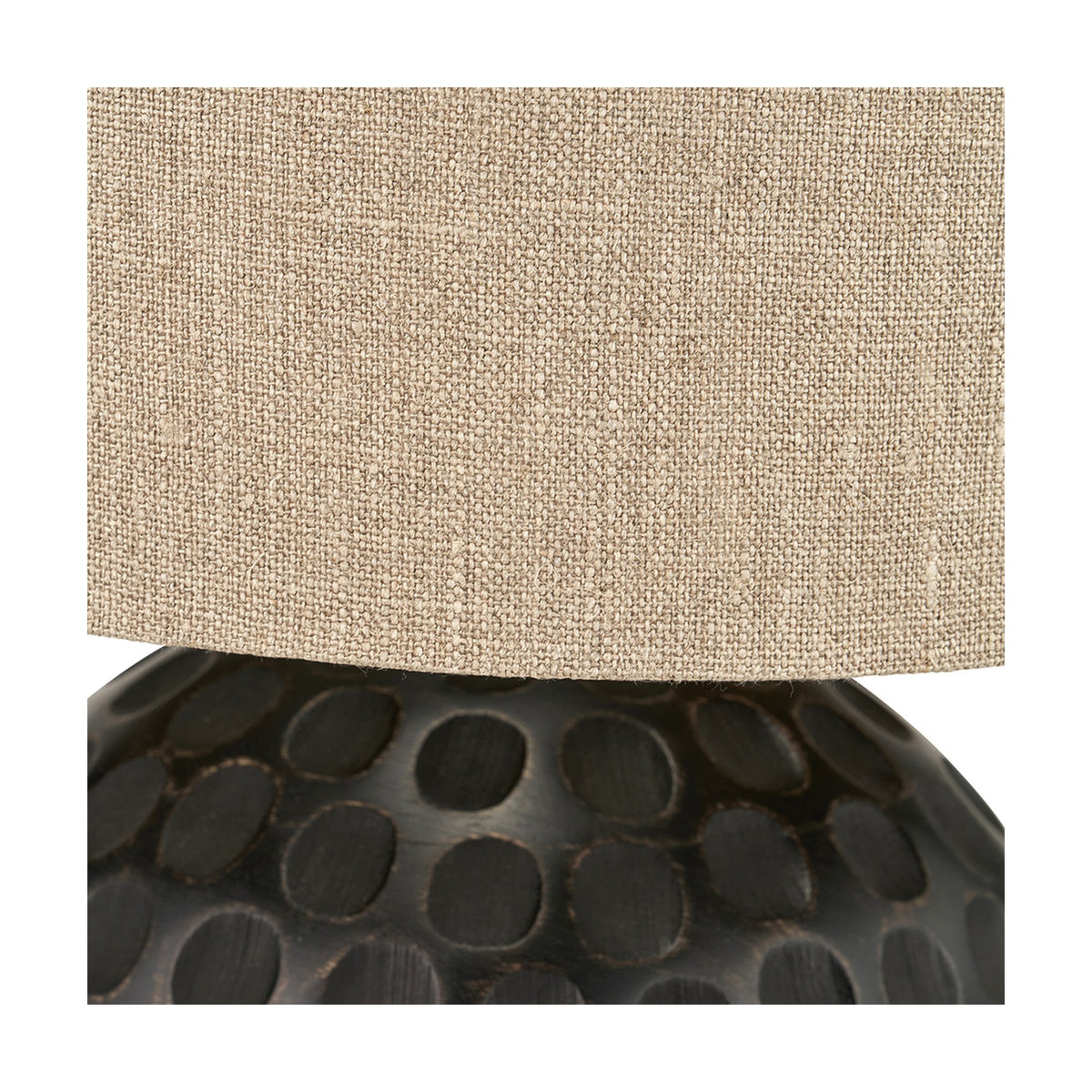 Close-up of the Dante Antique Black Mango Table Lamp showing the natural linen drum shade above a dark carved wood base with dotted texture.