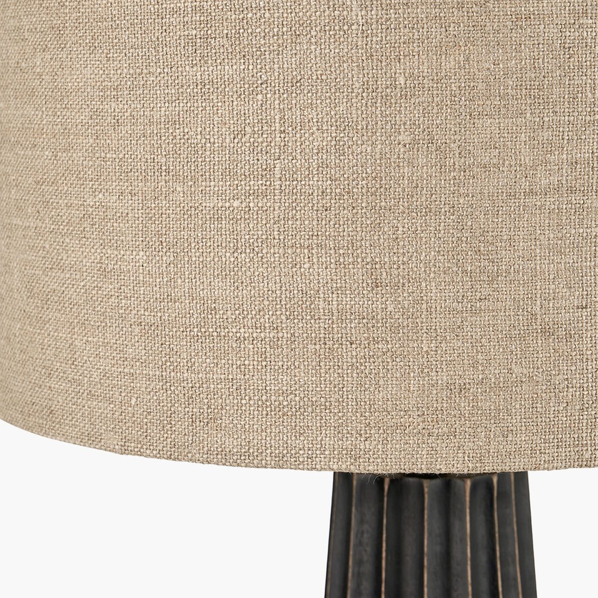 Close-up of the Draydon table lamp showing a natural linen cone shade above a black wash mango wood fluted base.