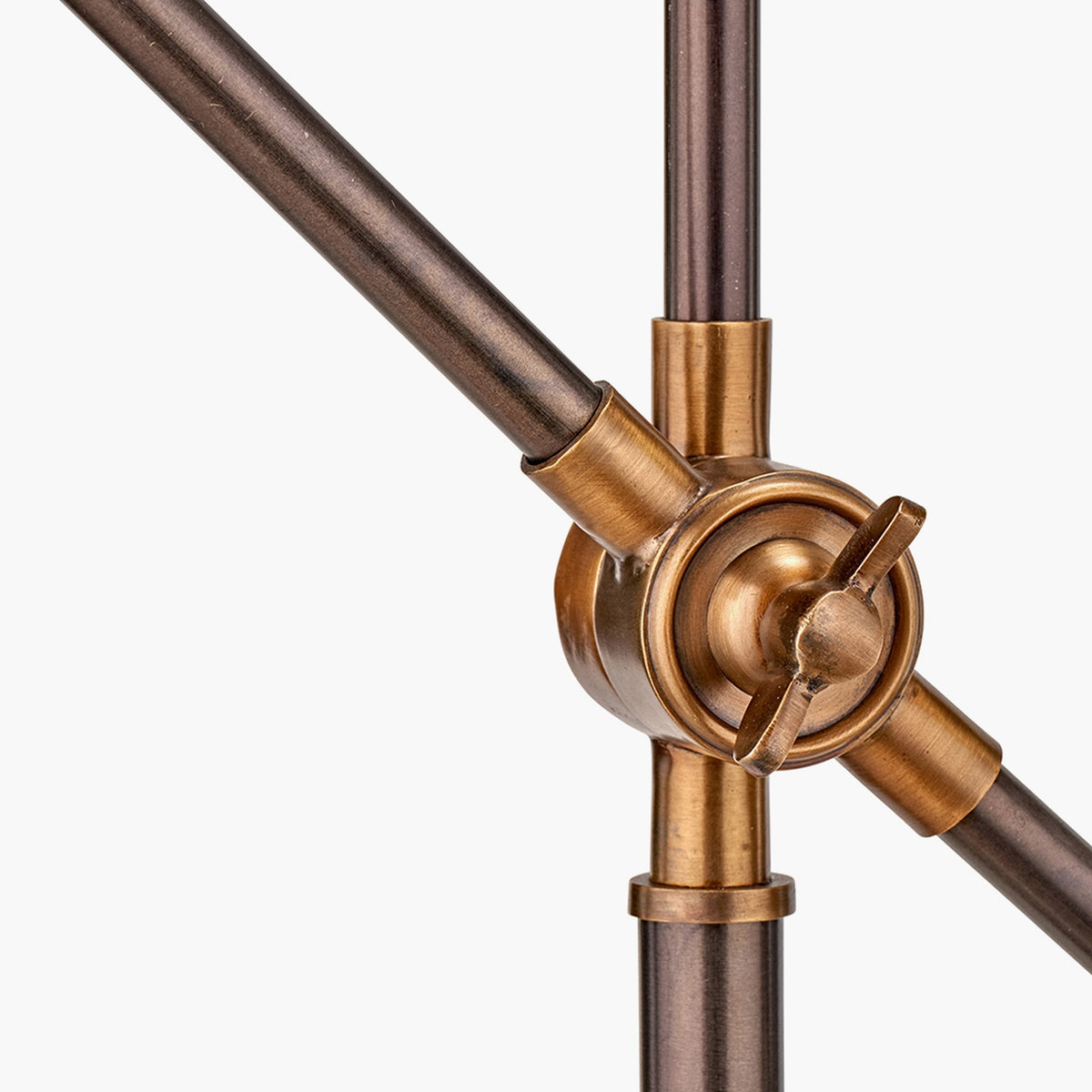 Close-up of the Emiliano adjustable task table lamp's pivot joint, showing antique bronze rods with a brass knuckle and wing-nut adjuster on a plain white background.