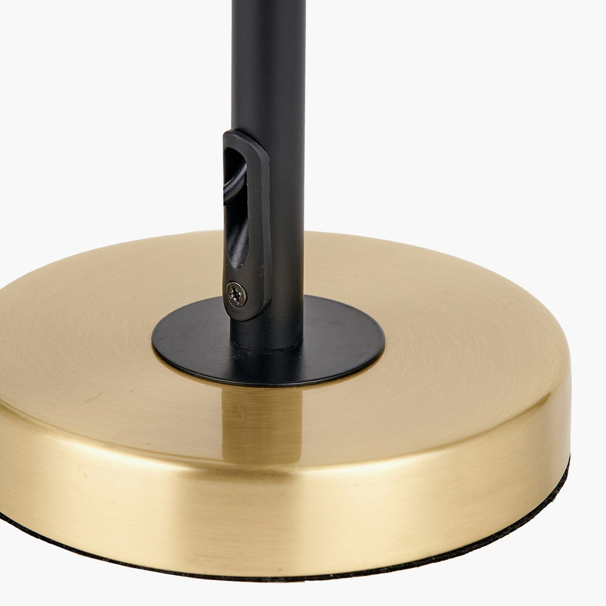 Close-up of the Bryce Black & Gold Iron Rise & Fall Table Lamp base, showing a round brushed brass plate with a black metal stem and screw fitting, on a plain white background.