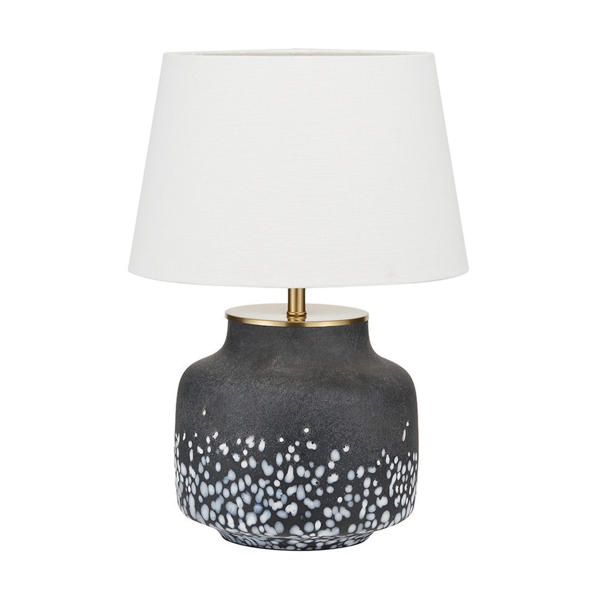 Etna table lamp with a black glass base featuring a white speckled pattern, brass-tone collar, and cream tapered shade on a plain white background.