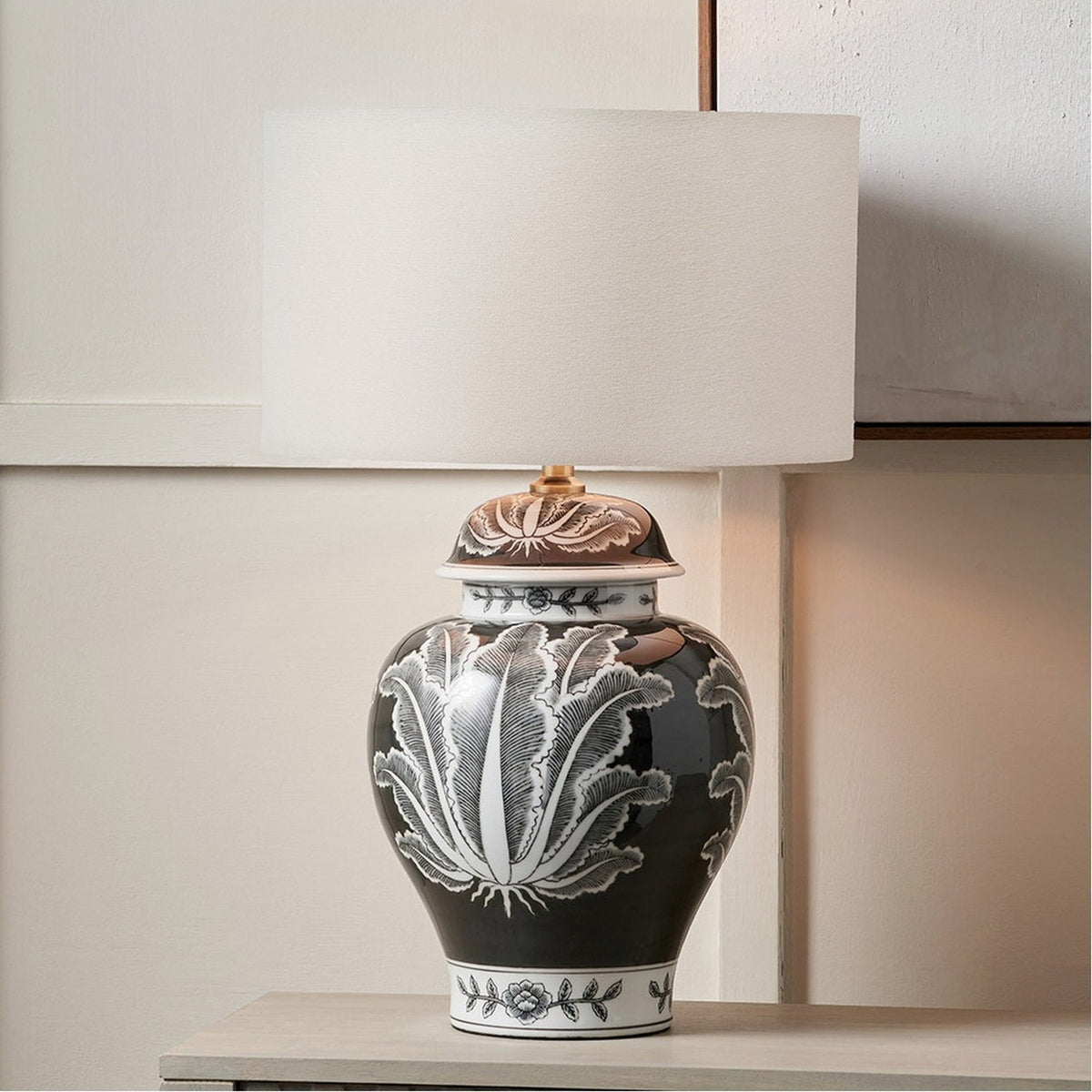Black & White Feather Ceramic Urn Table Lamp Base, 48cm, with cream drum shade, shown on a light wood console against a white panelled wall.