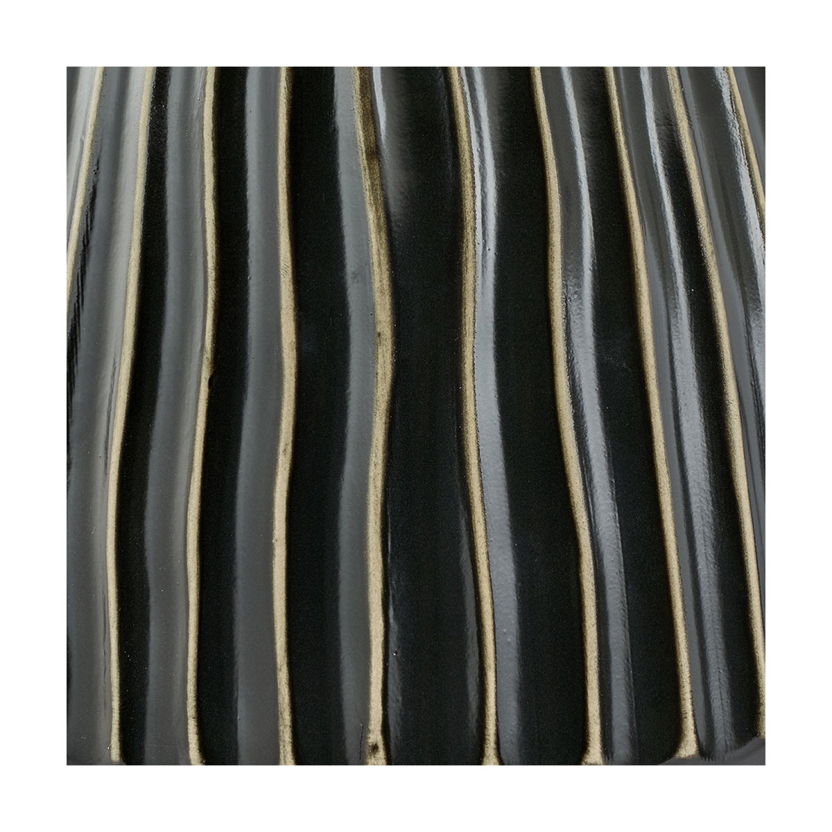 Close-up of the Artemis table lamp's black ceramic base showing ridged vertical texture with pale edges catching the light.