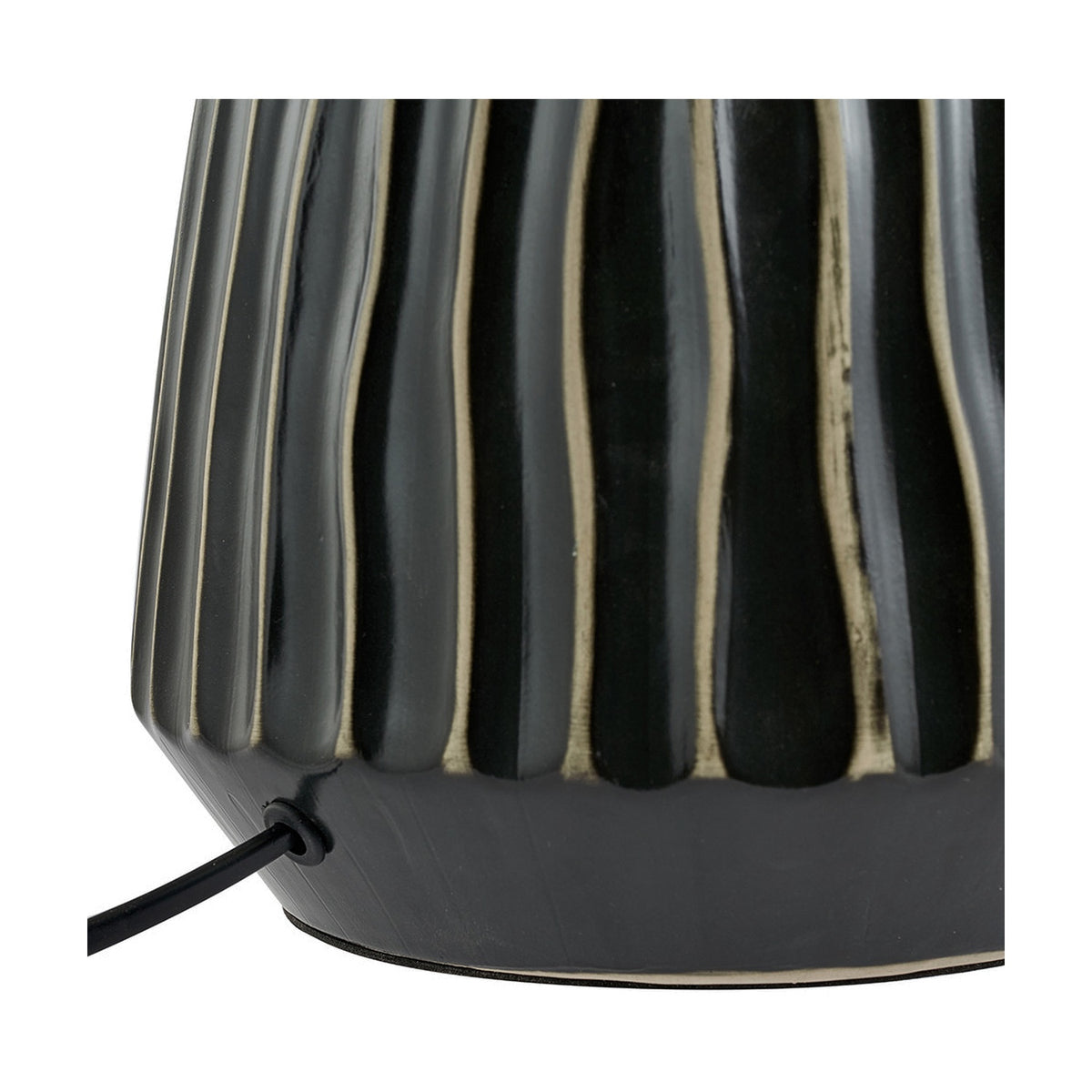 Close-up of the Artemis table lamp base showing ridged black ceramic texture with visible cord exit point on a plain background.