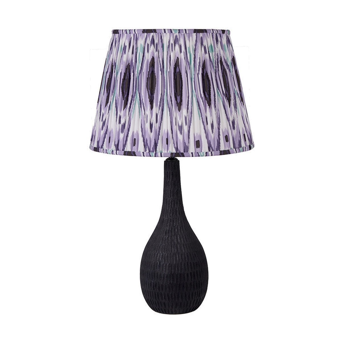 Ioan table lamp with a black engraved wood bottle-shaped base and a purple, white and black ikat-patterned drum shade, shown on a plain white background.