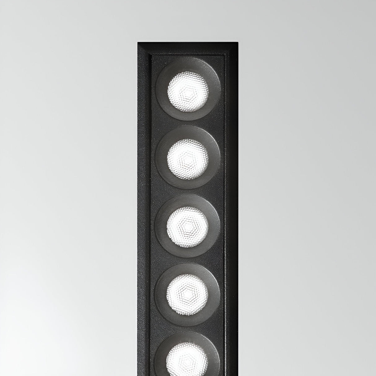 A vertical row of six Phosix Slim LED Recessed Downlights, each with a 20W power output and a 3000K color temperature, is embedded in a sleek black frame against a plain light gray background. These downlights emit a bright, even glow that showcases their energy efficiency and slim design while enhancing the minimalistic aesthetic.