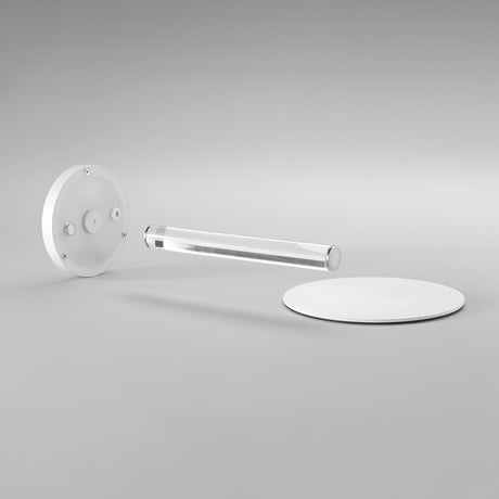 Minimalist photo featuring the contemporary design of the Solixis LED Table Lamp 3.6W 3000K - White: it includes three geometric elements—a circular white base, a clear cylindrical rod at its core, and a round white disc in the background—all arranged on a light gray surface. Ideal for battery-operated elegance.