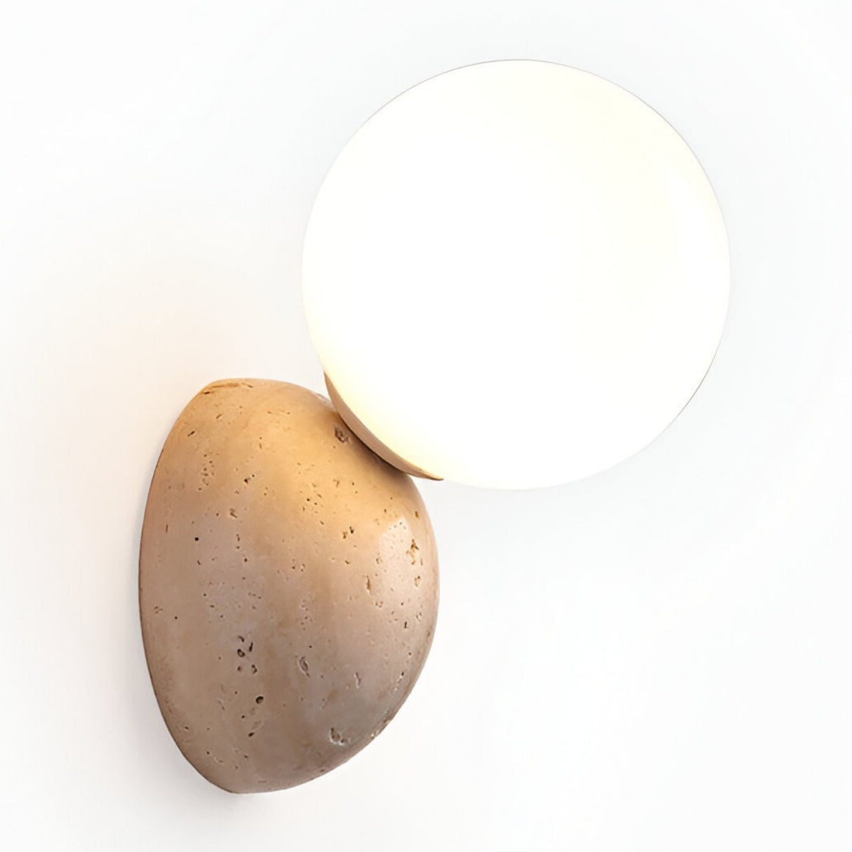 The Belaro 1 Light Globe Travertine Wall Light in light beige features a smooth white glass globe shade set on a textured oval travertine base, creating an elegant accent for any white wall.