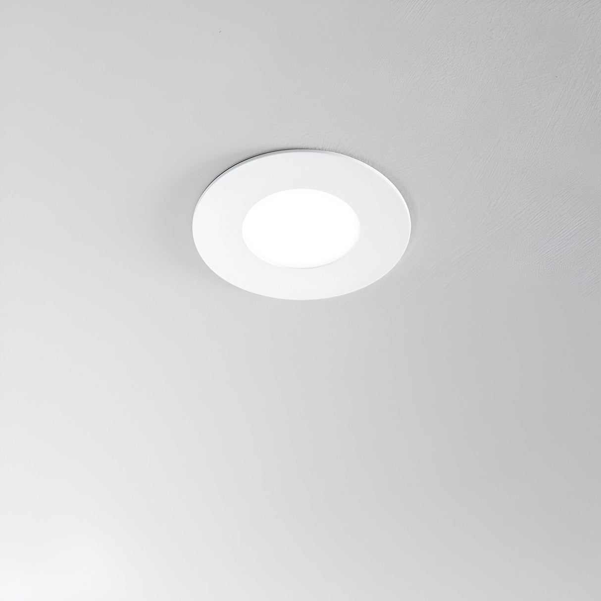 The Solix LED Recessed Downlight - 7W, 3000K, in white emits a warm glow against the smooth, light-colored ceiling. Its modern and minimalist design provides an energy-efficient lighting solution for any contemporary space.