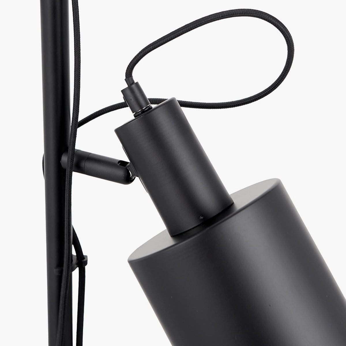 Close-up of the Aaron Black Iron Task Floor Lamp's cylindrical shade and adjustable joint in matte black metal, with black fabric cable, against a plain white background.