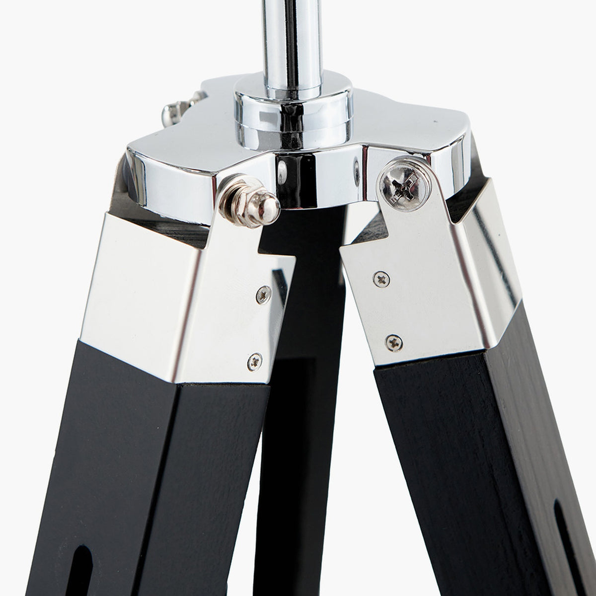 Close-up of the Hereford tripod floor lamp's chrome hub joining black wooden legs with visible screws, set against a plain white background.