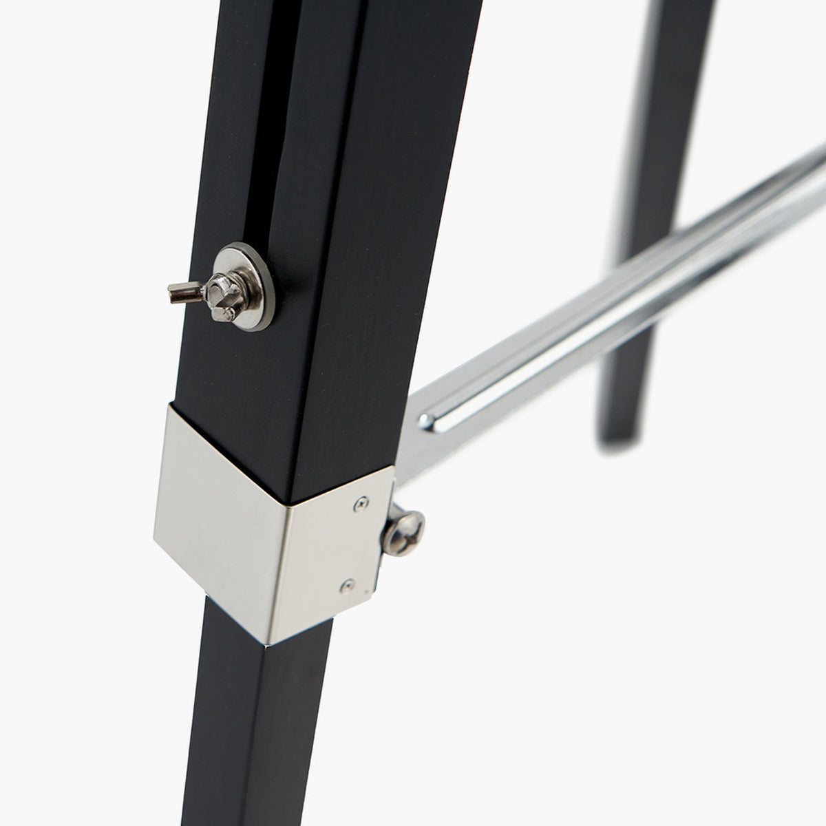Close-up of the Hereford Silver & Black Tripod Floor Lamp joint, showing a black wooden leg with chrome corner bracket, knob and screw fittings.