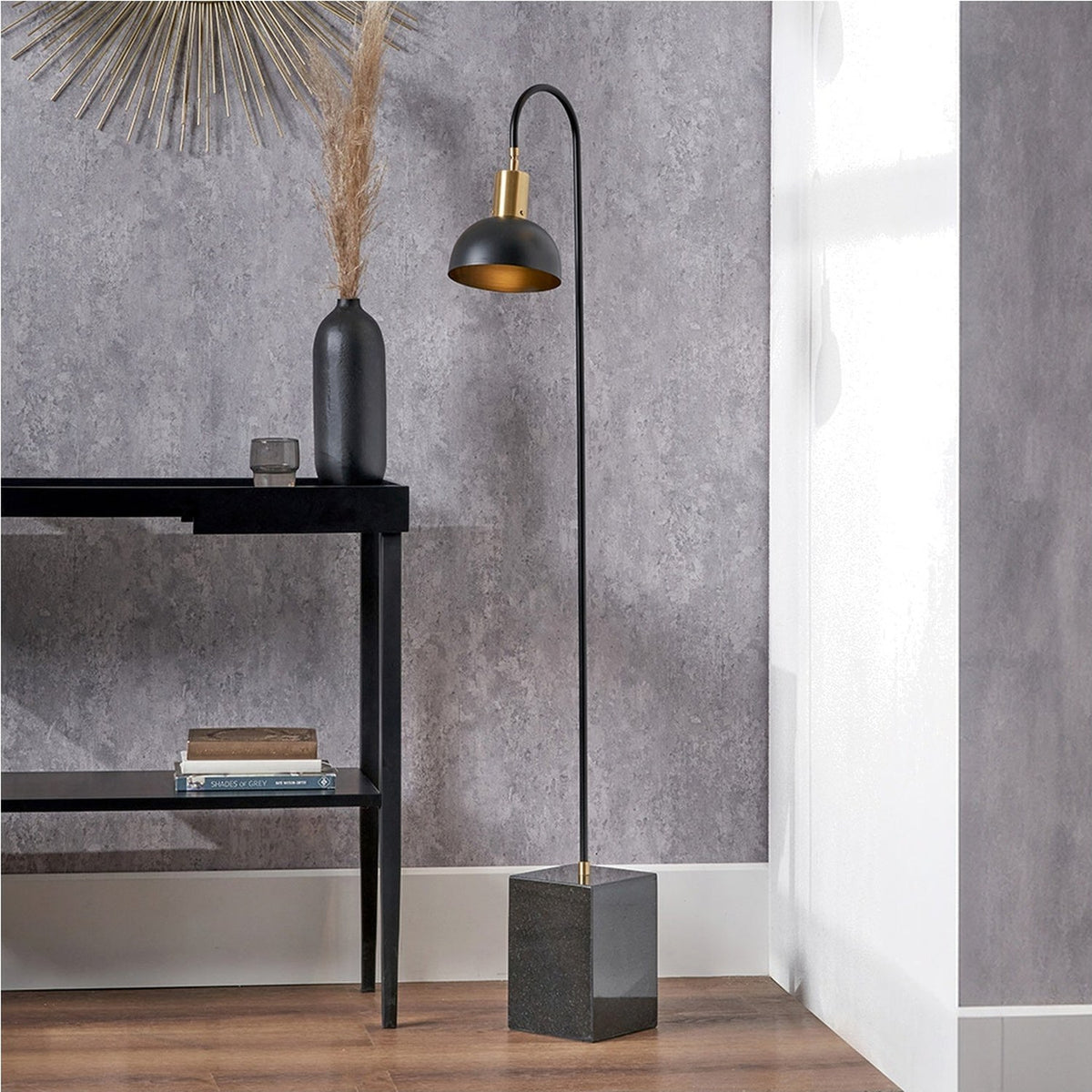 Mayfair Matt Black Domed Task Floor Lamp, 141cm, with curved arm, brass accents and square marble base, shown beside a black console table in a living room setting.