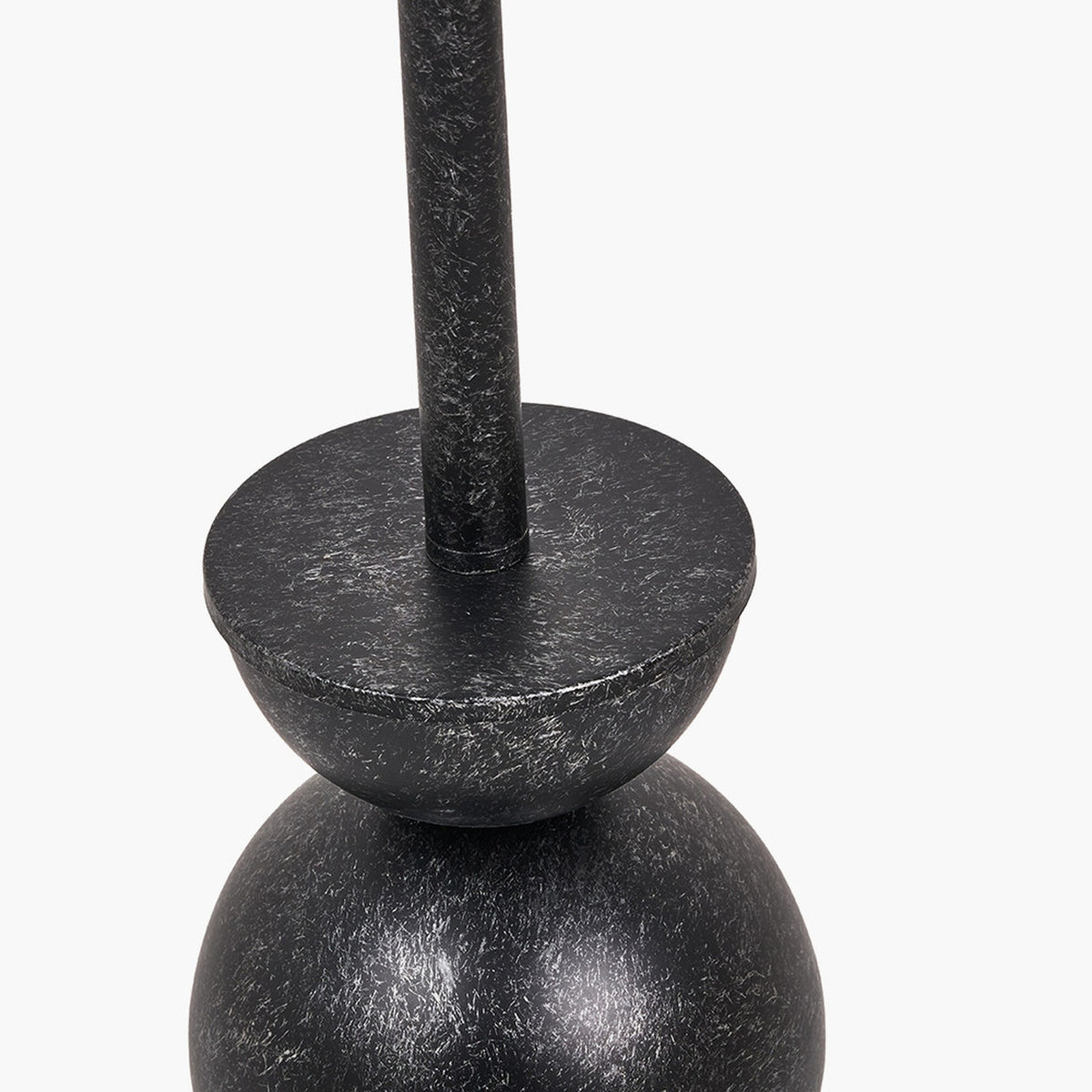 Close-up of the Vala floor lamp's graphite metal ball base and neck, showing a textured effect finish where the slim rod meets a rounded, bowl-like joint.