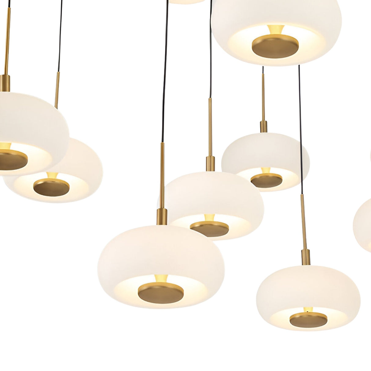 Close-up of Niori Aurevia chandelier showing white alabaster domes with brushed brass stems and discs suspended on black cables at staggered heights.
